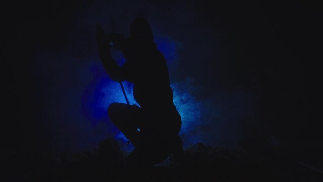 Medieval warrior assassin ninja with sword in aggressive pose in smoke