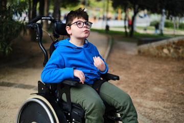 Disabled boy in wheelchair enjoying the day outdoors in the park.