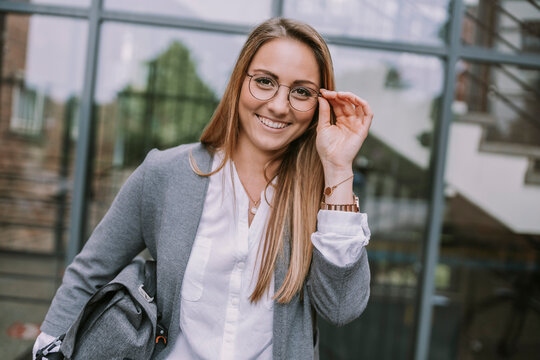 Happy woman adjusting eyeglasses outside building