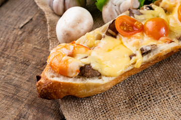 Pizza on a baguette with shrimp and cheese close-up. Baked sandwich. Selective focus.
