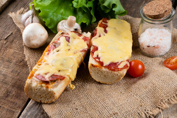 Piperoni pizza on a baguette on a wooden table.