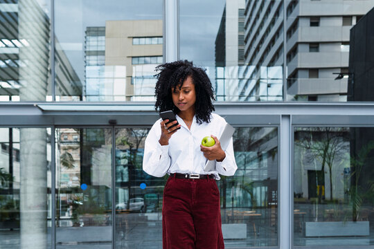 Businesswoman with curly hair using mobile phone at office park