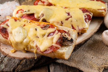 Pizza on a baguette with cheese and sausages close-up. Homemade baking.