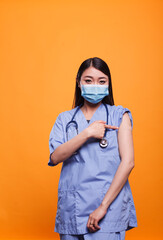 Responsible healthcare nurse promoting vaccination against coronavirus epidemic while wearing a...