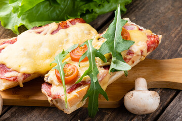Sandwich pizza on a baguette close-up.Pizza on a baguette with cheese, sausages and arugula....