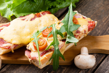 Sandwich pizza on a baguette close-up.Pizza on a baguette with cheese, sausages and arugula. Italian sandwich.
