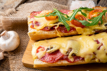 Homemade pizza sandwich cooked on a baguette with cheese, mushrooms and pepperoni. Close-up.