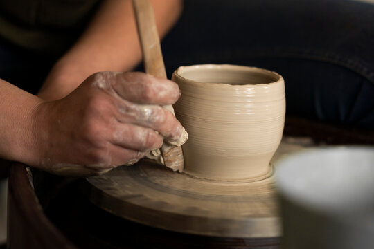 Woman with hand tool shaping clay pot at workshop