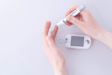 Human using a glucometer to measure and test blood glucose levels from a finger.