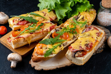 Homemade pizza cooked on a baguette with cheese and mushrooms and pepperoni sausages and arugula,...