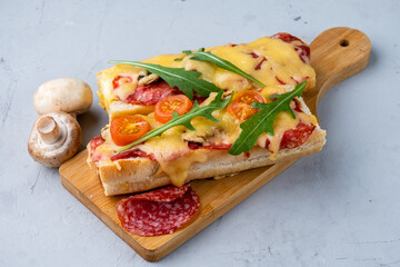 Homemade pizza sandwich, pizza cooked on a baguette with cheese, pepperoni sausages and mushrooms,...