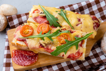 Homemade pizza on a baguette. Sandwich pizza with cheese and pepperoni sausages and mushrooms,...