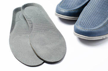 Orthopedic insoles and men's shoes. White background. The concept of prevention of diseases of the feet and flat feet. Comfort of wearing shoes