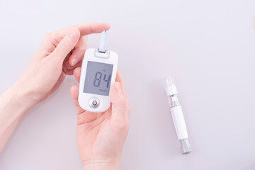 Human using a glucometer to measure and test blood glucose levels from a finger.