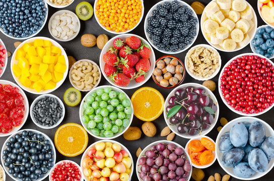 Berries, fruits and nuts on a black concrete background. Vegetarian food.