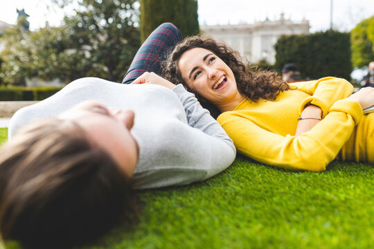 Cheerful young woman lying down with friend at park