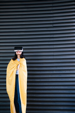 Smiling woman wearing VR googles in front of corrugated iron shutter