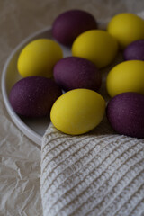 Bright and beautiful Easter eggs, purple and yellow, on a white plate. Christ is risen. Happy Easter.