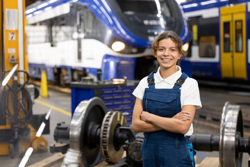 Smiling young trainee standing with arms crossed in warehouse at factory