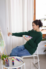 Creative of art concept, Young asian woman hold paintbrush in front of canvas to measure proportion