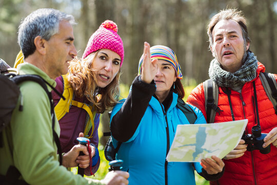 Woman with map guiding friends in forest