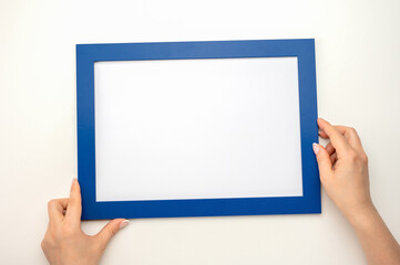 Obraz premium Holding frame mockup. Photo Mockup. Woman hands hold blue frame. For frames and posters design. Frame size A4. incline blank photo frame border with copy space in hands close up