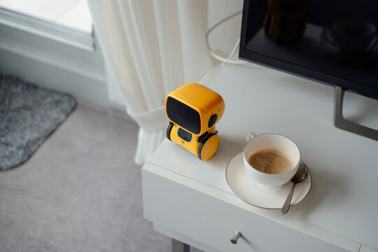 AI toy robot by coffee cup on table at home