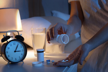Obraz na płótnie Canvas Woman with pills in bedroom at night, closeup. Insomnia concept