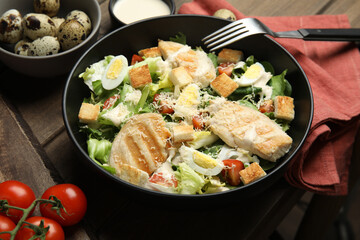 Fototapeta na wymiar Delicious Caesar salad in bowl on wooden table