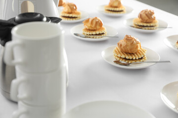 Many delicious waffles with cream served on white table for coffee break