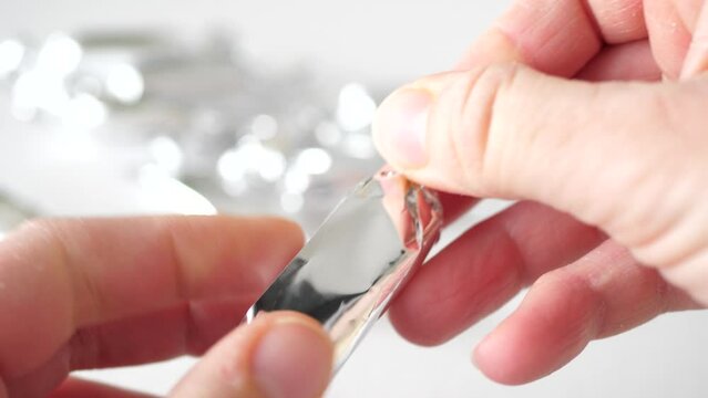 Human hands taking and unwrapping silver candy