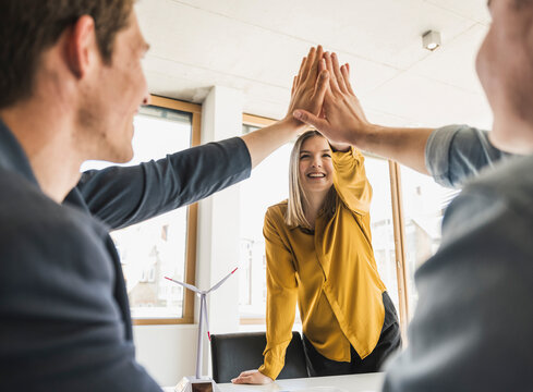 Happy business team high fiving in office