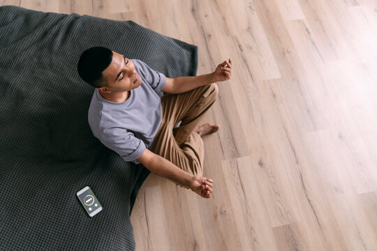 Young man practicing breathing exercise by smart phone with timer at home - Powered by Adobe