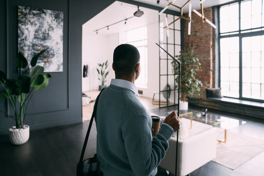 Young man holding disposable coffee cup arriving at home