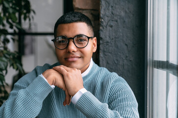 Young man wearing eyeglasses by window at home