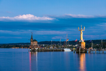 Germany, Baden-Wurttemberg, Konstanz, Harbor on shore of Lake Constance at dusk with lighthouse and statue of Imperia in background