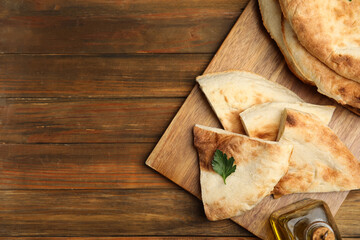 Cut fresh pita bread on wooden table, top view. Space for text