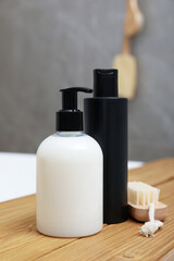 Bottles of shower gels and brush on wooden table in bathroom
