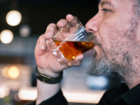 Portrait Of A Handsome Mature Man Drinking A Glass Of Neat Whiskey At The Bar Or Pub.