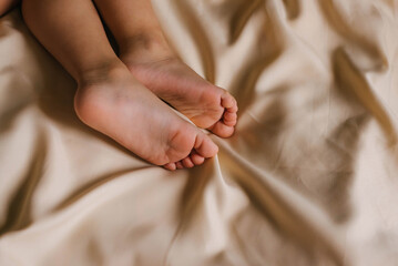 Children's feet and heels on a white bed. Infant baby is sleeping in his crib. Importance of sleep...
