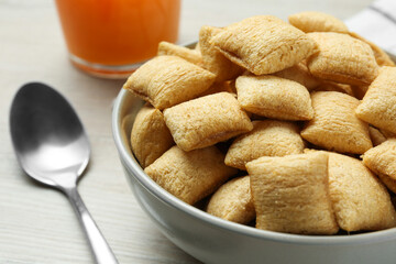 Bowl of sweet crispy corn pads and juice on white wooden table, closeup. Breakfast cereal