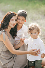 Fototapeta premium Happy young woman with children on wheat summer field. Happy motherhood.