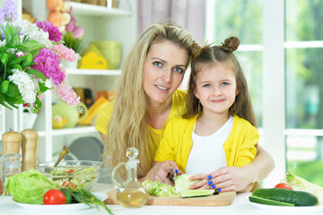 smiling mother and daughter cooking together