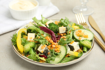 Delicious salad with lentils, vegetables and cheese served on light grey table