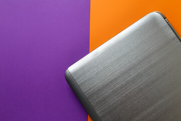the laptop lies on a multi-colored background. orange and purple trend background.