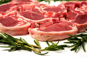 Fresh lamb chops and green rosemary herb on white background. Meat industry product. Butcher craft