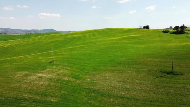 Europe, Italy , April 2022 - Drone aerial view of  Tuscany countryside  landscape in Asciano , Val D'orcia , Siena -  Crete Senesi touristic attraction - green hill with yellow flowers and blue sky 