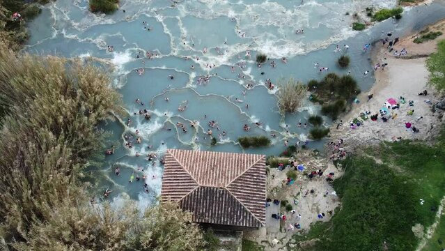 Europe, Drone aerial view of natural Spa and Thermal Springs of Saturnia, Grosseto, Tuscany, Italy. Unrecognizable Tourists Taking Healthy Bath in Hot Springs Waterfall. Relax and Spa Concept
