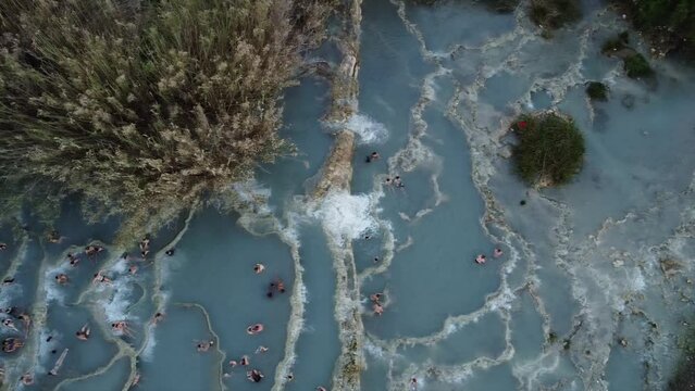Europe, Drone aerial view of natural Spa and Thermal Springs of Saturnia, Grosseto, Tuscany, Italy. Unrecognizable Tourists Taking Healthy Bath in Hot Springs Waterfall. Relax and Spa Concept