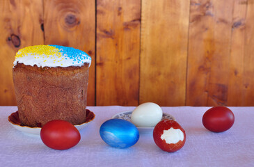 Easter in Ukraine, paska and painted eggs on the table, the wooden wall on the background